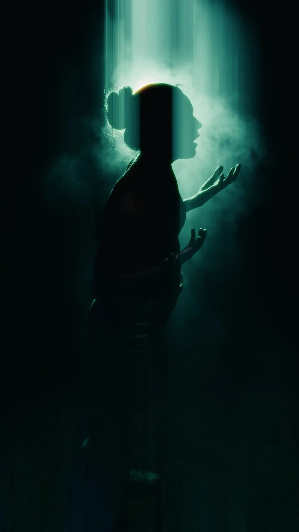 Silhouette of Jessi Woodruff with open hands in a beam of light and fog