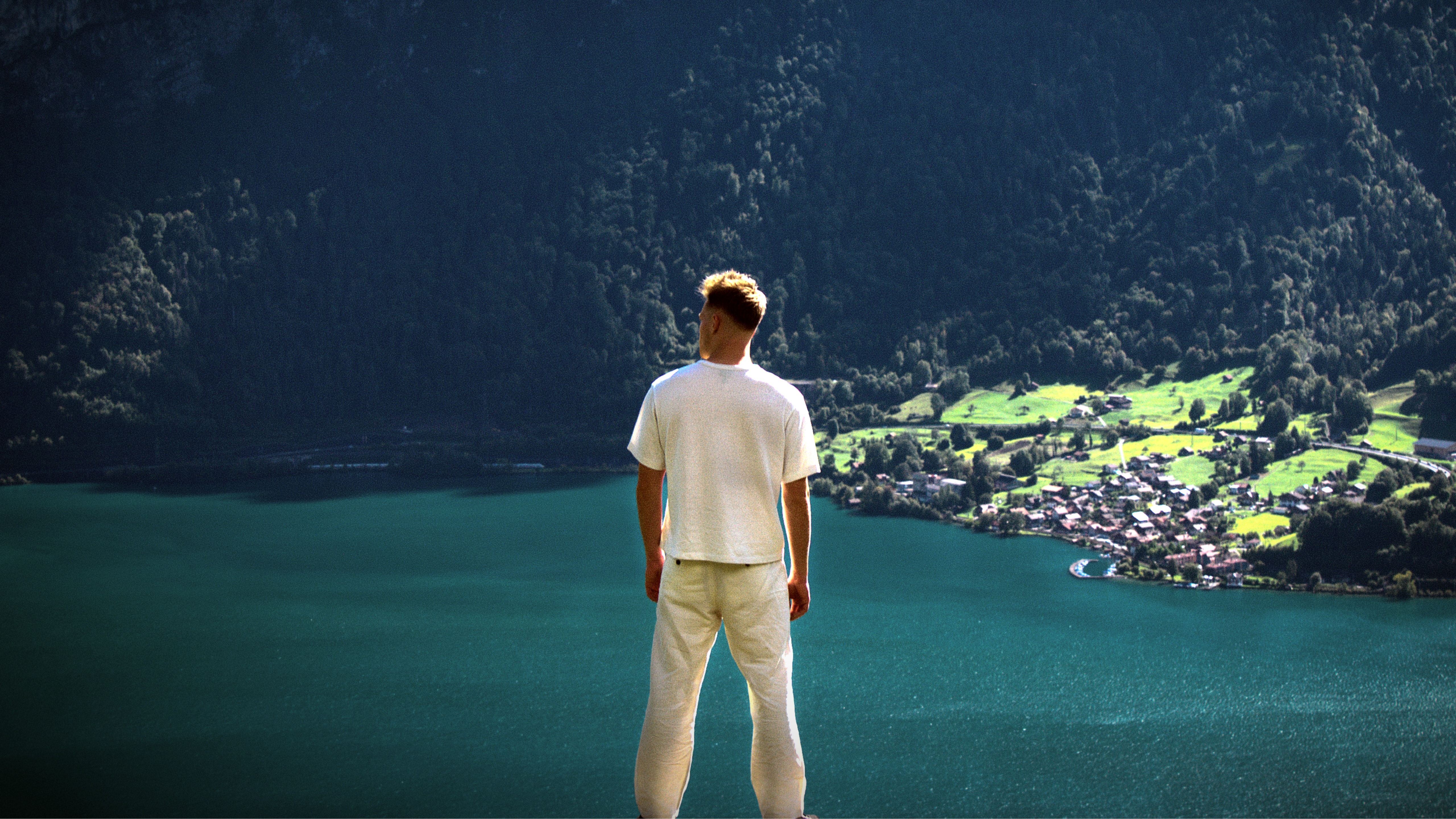 Lukas Goss looking out over a turquoise alpine lake
