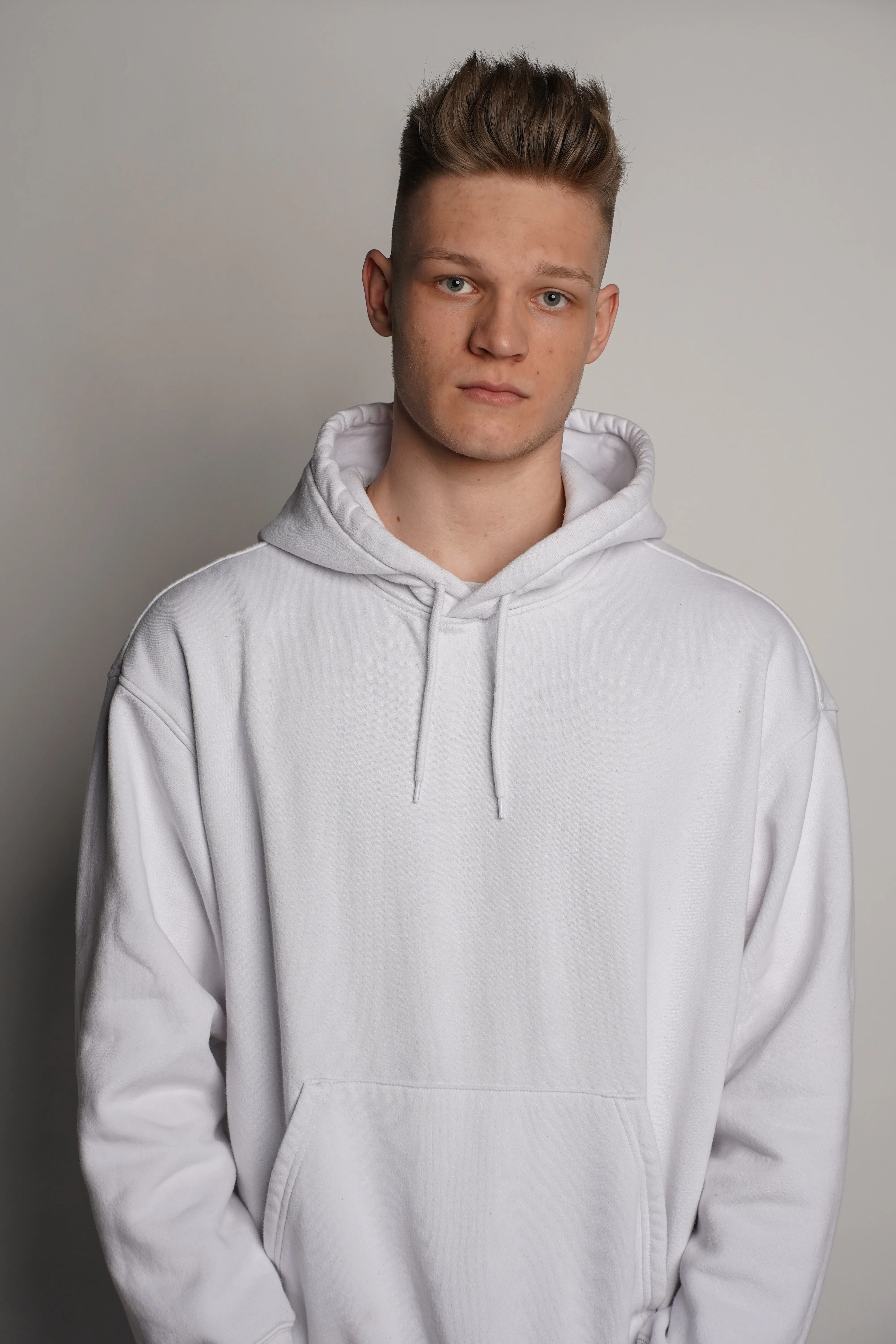 Studio portrait of Lukas Goss in a white hoodie